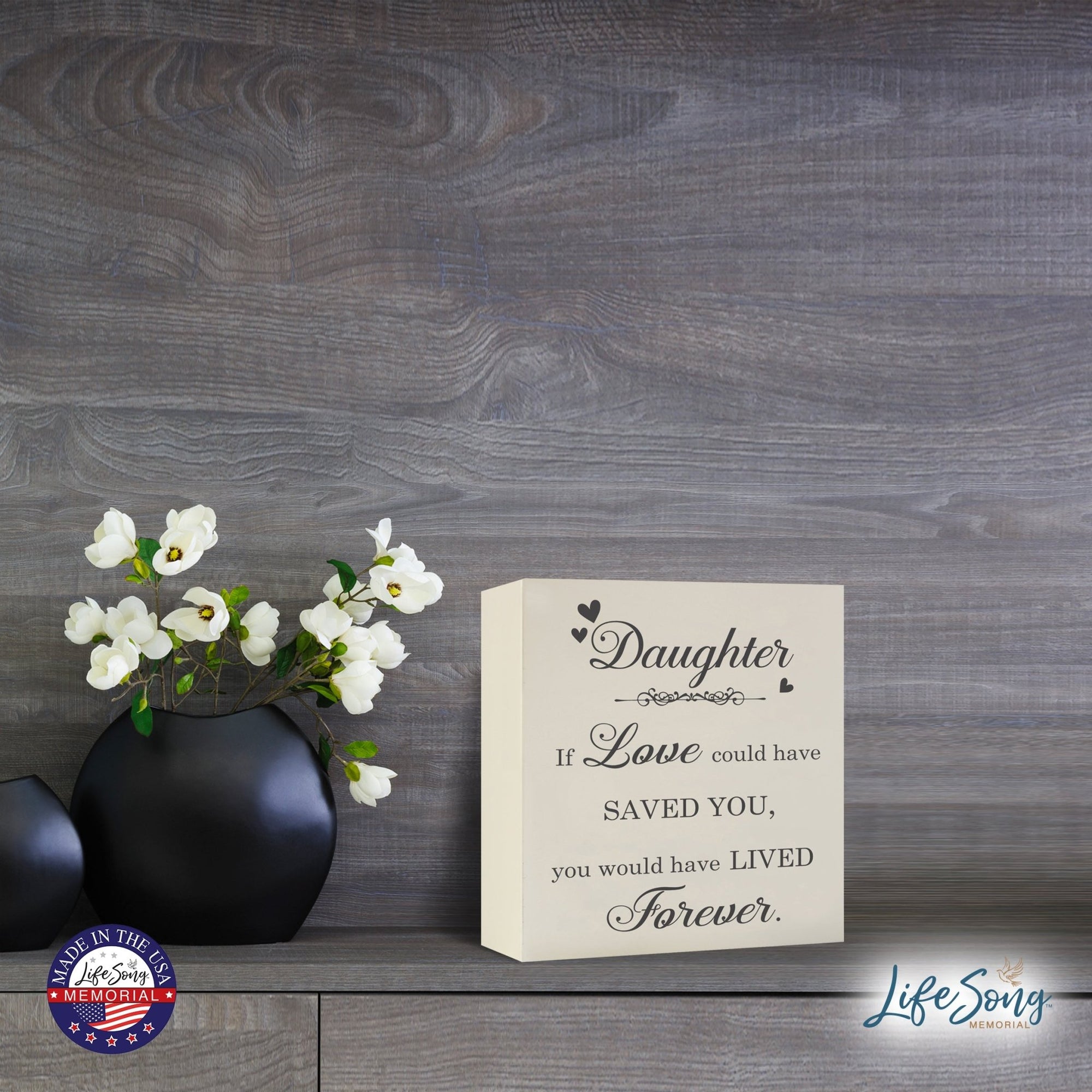 Lifesong Milestones Memorial Shadow Box Urn For Human Ashes showcased on a wooden tabletop, adorned with sophisticated black vases holding delicate white flowers, serving as a heartfelt keepsake with the touching message.