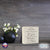 Lifesong Milestones Memorial Shadow Box Urn For Human Ashes showcased on a wooden tabletop, adorned with sophisticated black vases holding delicate white flowers, serving as a heartfelt keepsake with the touching message.